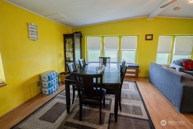 a kitchen with stainless steel appliances a stove a refrigerator a dining table and chairs with wooden floor