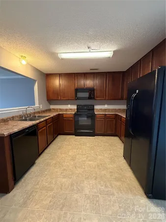 a large kitchen with granite countertop stainless steel appliances and wooden cabinets