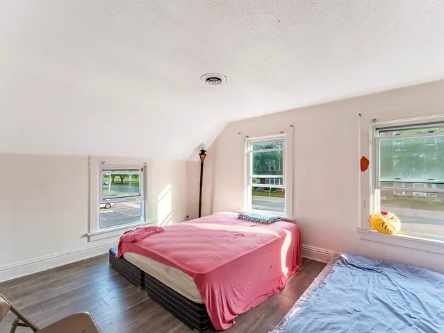 a spacious bedroom with a bed and wooden floor