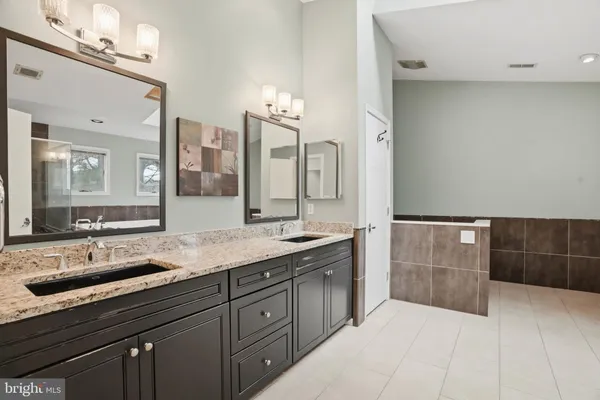 a bathroom with a granite countertop sink a toilet a mirror and shower