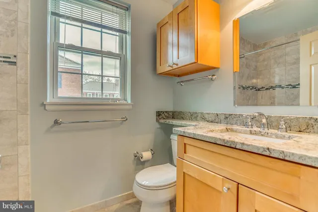 a bathroom with a granite countertop toilet sink and mirror