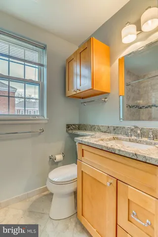 a bathroom with a granite countertop toilet sink and mirror
