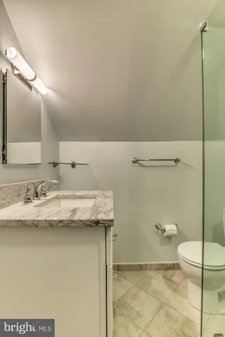 a bathroom with a granite countertop sink a toilet and a mirror