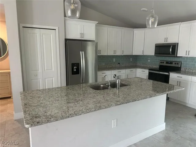 a kitchen with stainless steel appliances granite countertop a refrigerator a stove and a sink with granite countertops