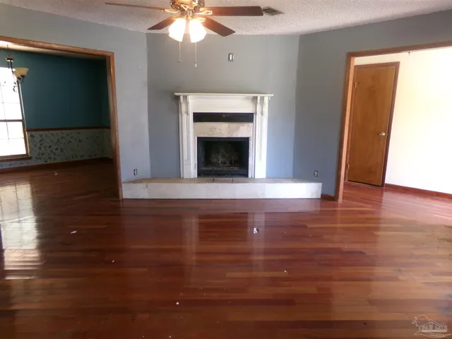 a view of an empty room with wooden floor fireplace and a window