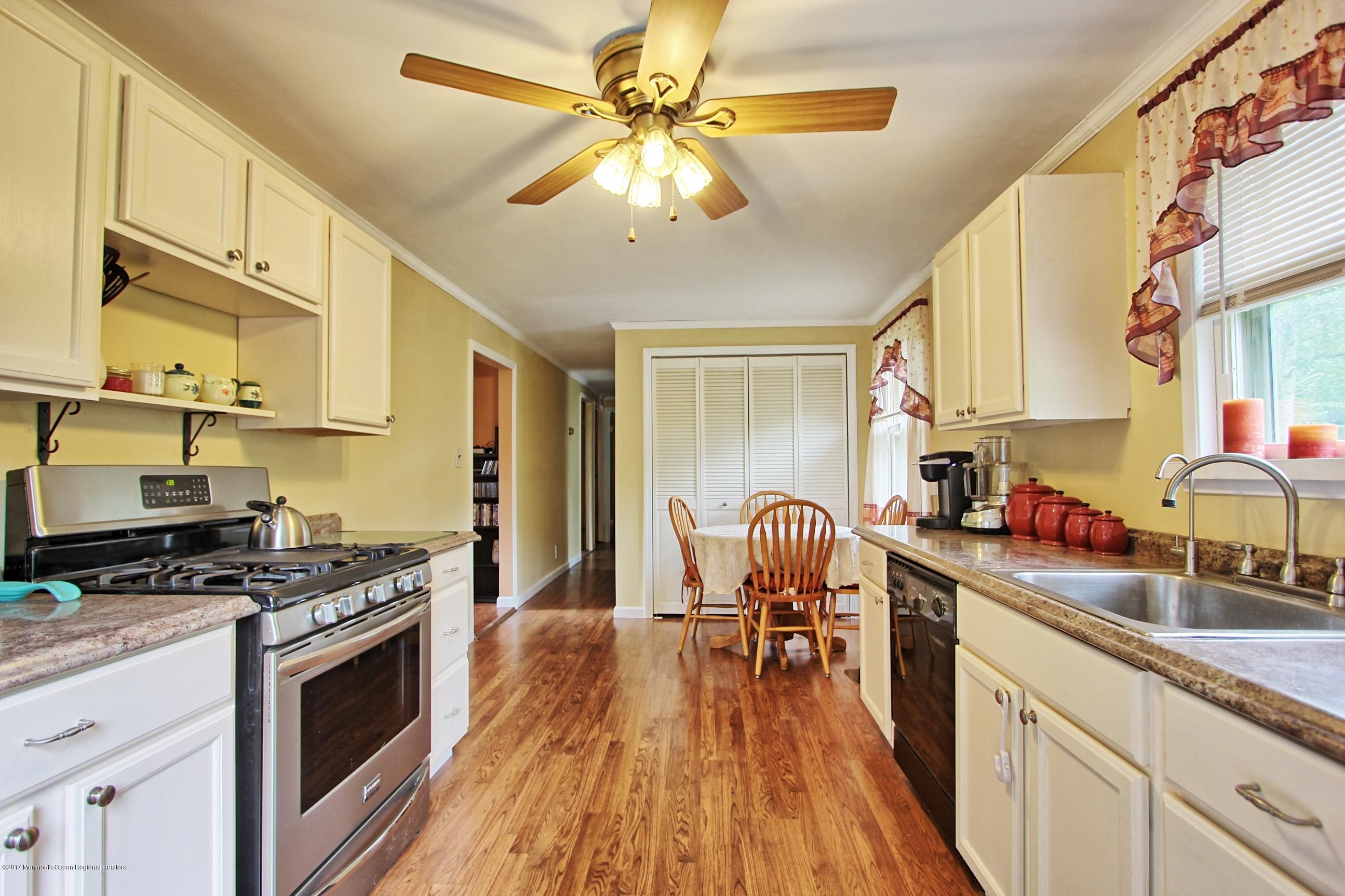 49 Siloam Road Freehold, NJ 07728 - Photo 7 of 38 a kitchen with stainless steel appliances a stove a sink dishwasher and cabinets with wooden floor
