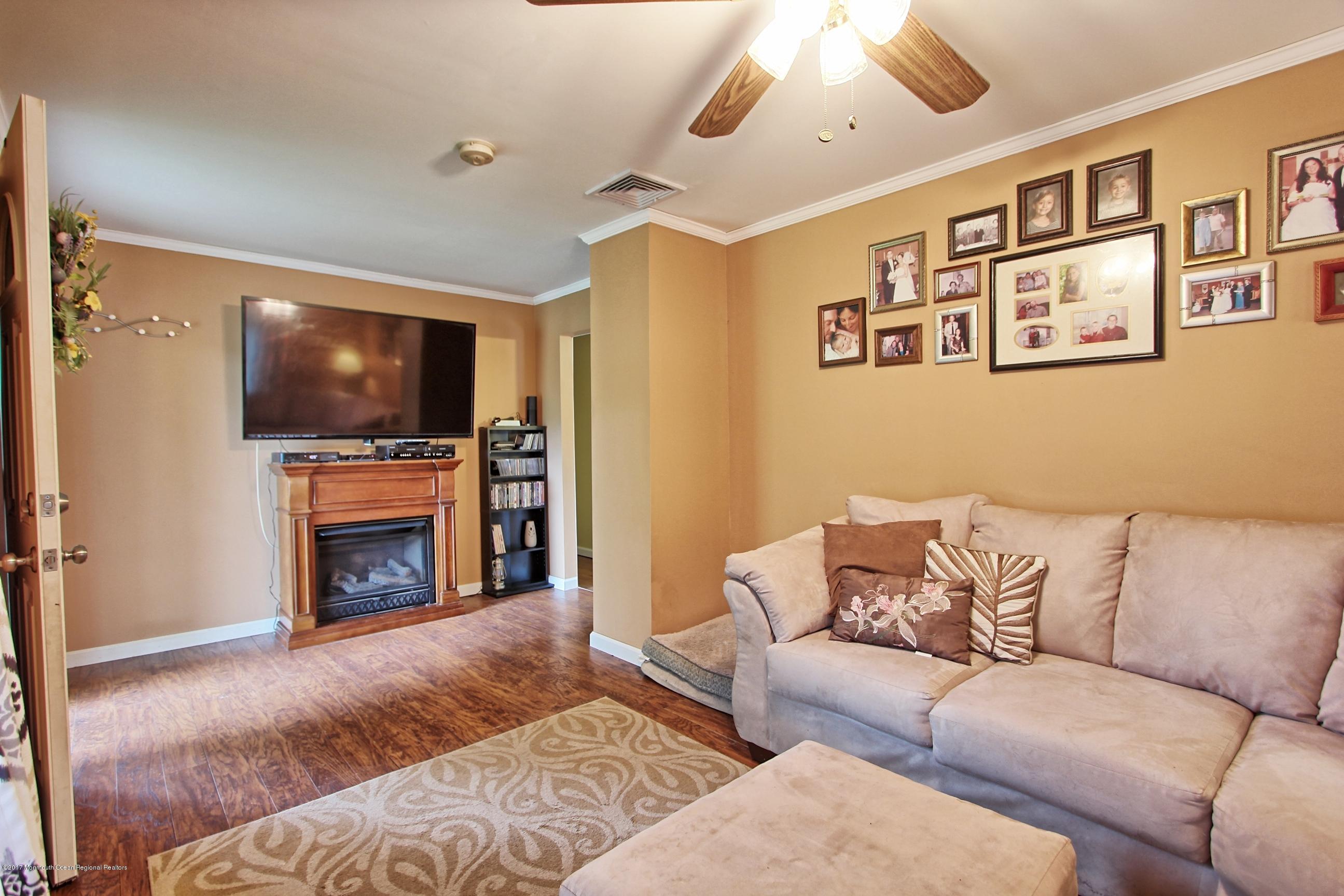 49 Siloam Road Freehold, NJ 07728 - Photo 10 of 38 a living room with furniture a fireplace and a flat screen tv