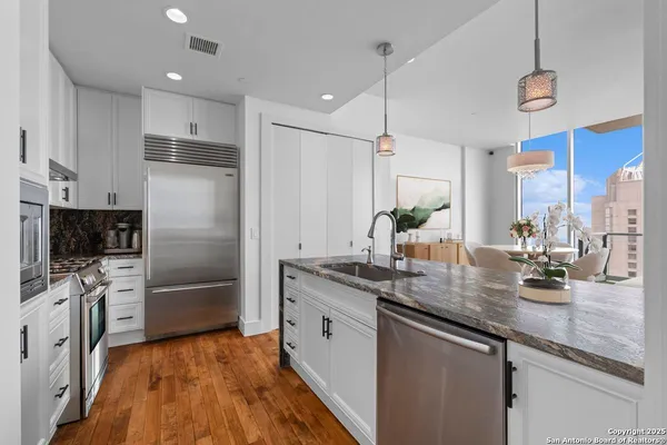 a kitchen with stainless steel appliances granite countertop a sink a stove and a refrigerator