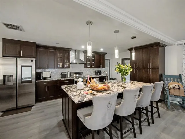 a kitchen with a refrigerator a kitchen island a stove a table and chairs