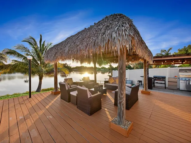 a view of a patio with couches and table under an umbrella with wooden floor