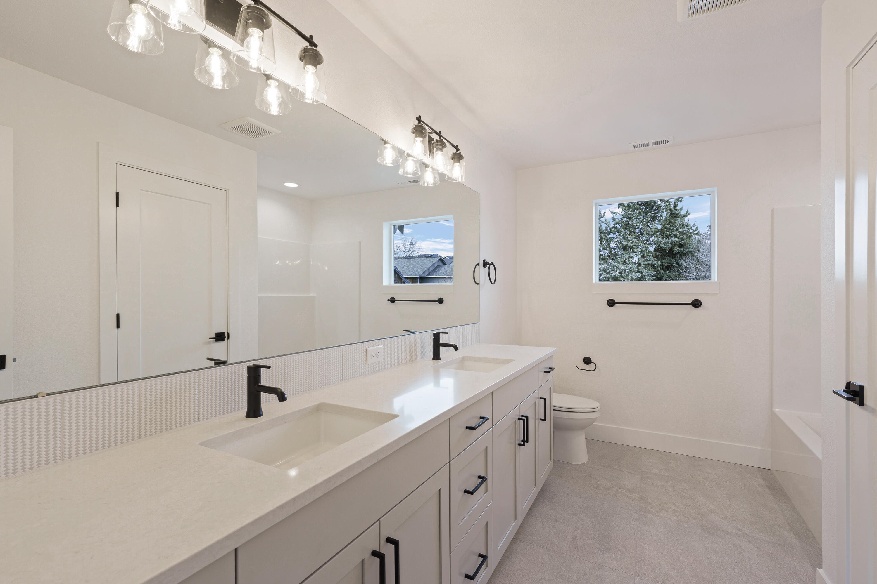 4383 Southwest Rhyolite Place, Unit 22 Redmond, OR 97756 - Photo 30 of 44 a bathroom with a double vanity sink a toilet and a mirror