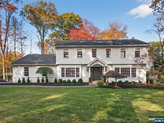 a front view of a house with a garden and trees