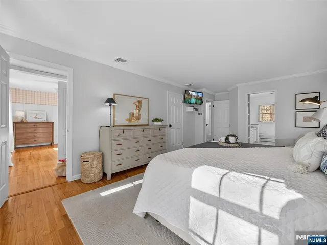 a spacious bedroom with a bed and wooden floor