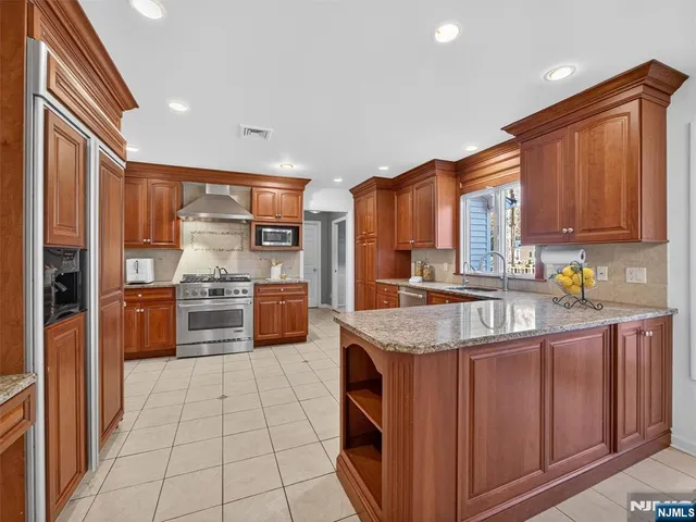 a kitchen with stainless steel appliances granite countertop a stove a sink and a refrigerator