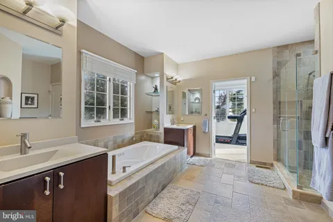 a spacious bathroom with a tub sink shower and mirror