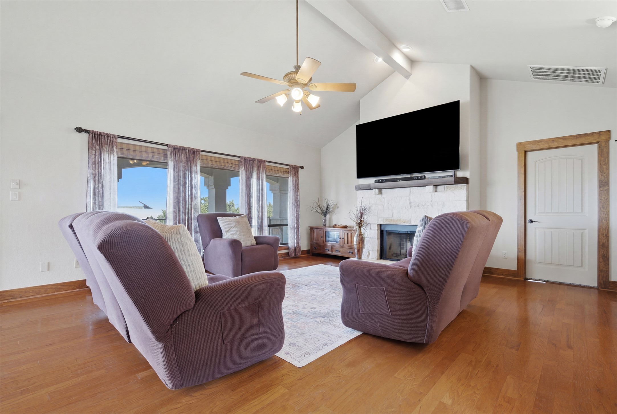700 Augusta Circle Point Venture, TX 78645 - Photo 3 of 35 A well-lit living area showcases hardwood floors, a stone fireplace, and lofty vaulted ceilings.