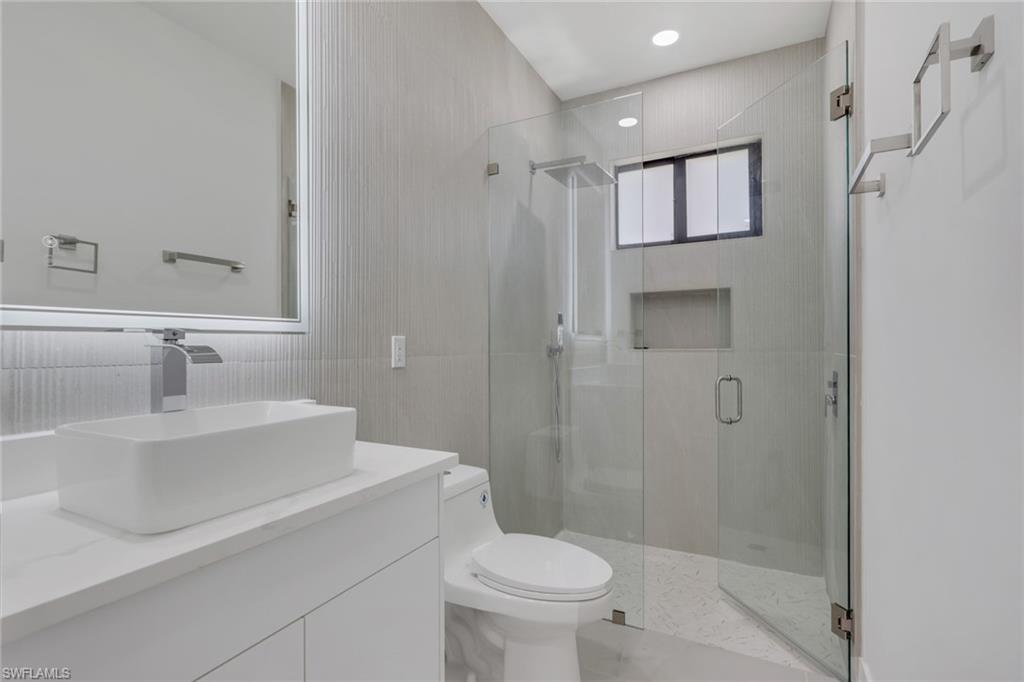 730 29th Street Southwest Naples, FL 34117 - Photo 33 of 50 Full bath with double vanity, a soaking tub, tile walls, and light marble finish flooring