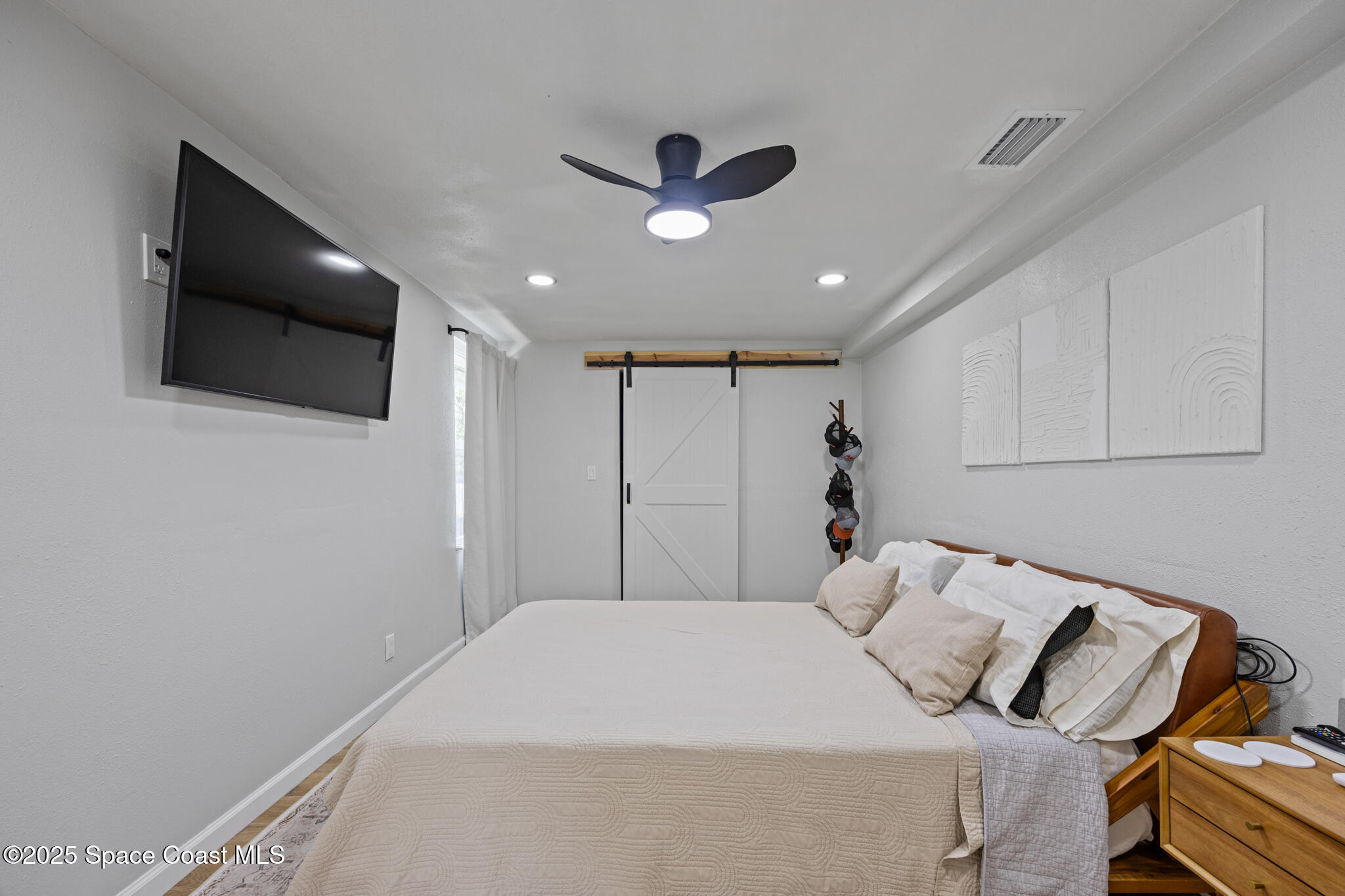 115 Primrose Lane Melbourne, FL 32901 - Photo 14 of 22 a bedroom with a bed and a flat screen tv