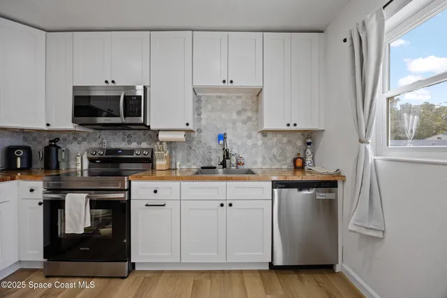 a kitchen with stainless steel appliances granite countertop a stove a sink and a white cabinets
