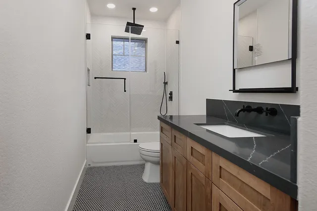 a bathroom with a granite countertop sink toilet and shower