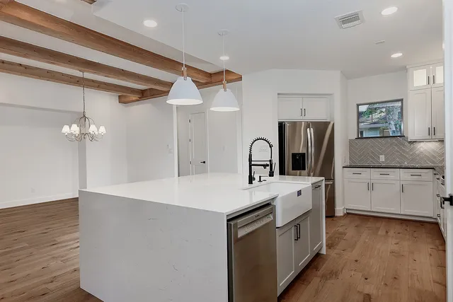 a large white kitchen with a stove a sink a refrigerator and chandelier