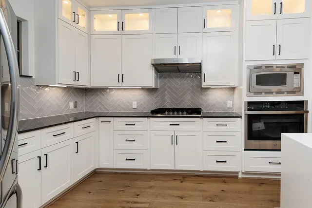 a kitchen with granite countertop white cabinets and white stainless steel appliances