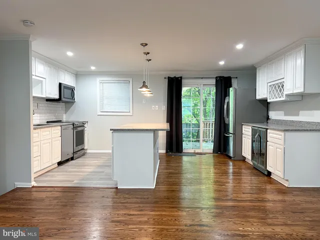 a kitchen with stainless steel appliances granite countertop a stove top oven a sink dishwasher and a refrigerator with wooden floor