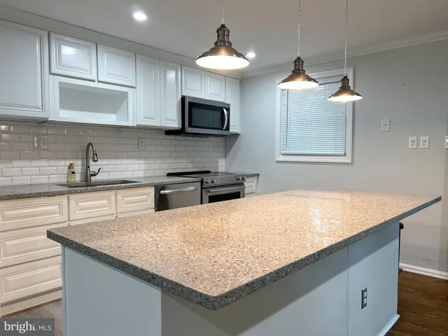 a kitchen with kitchen island granite countertop a sink and a stove