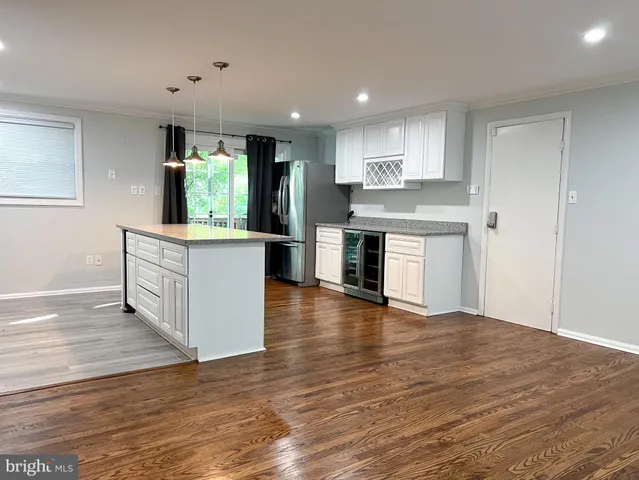 a kitchen with stainless steel appliances granite countertop a wooden floors and white walls