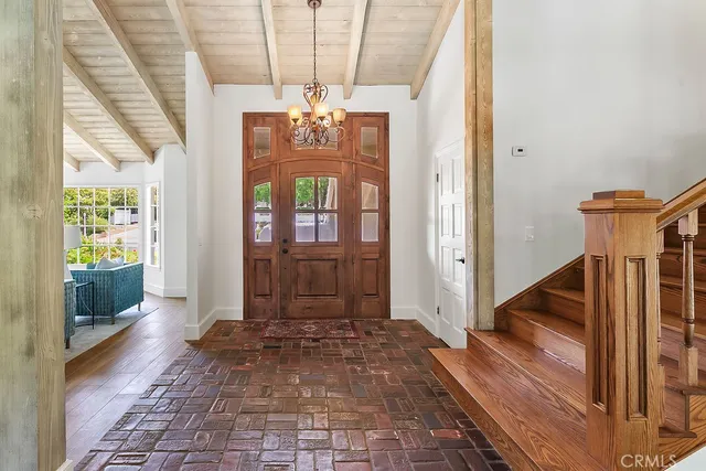 a view of a hallway with wooden floor and chandelier