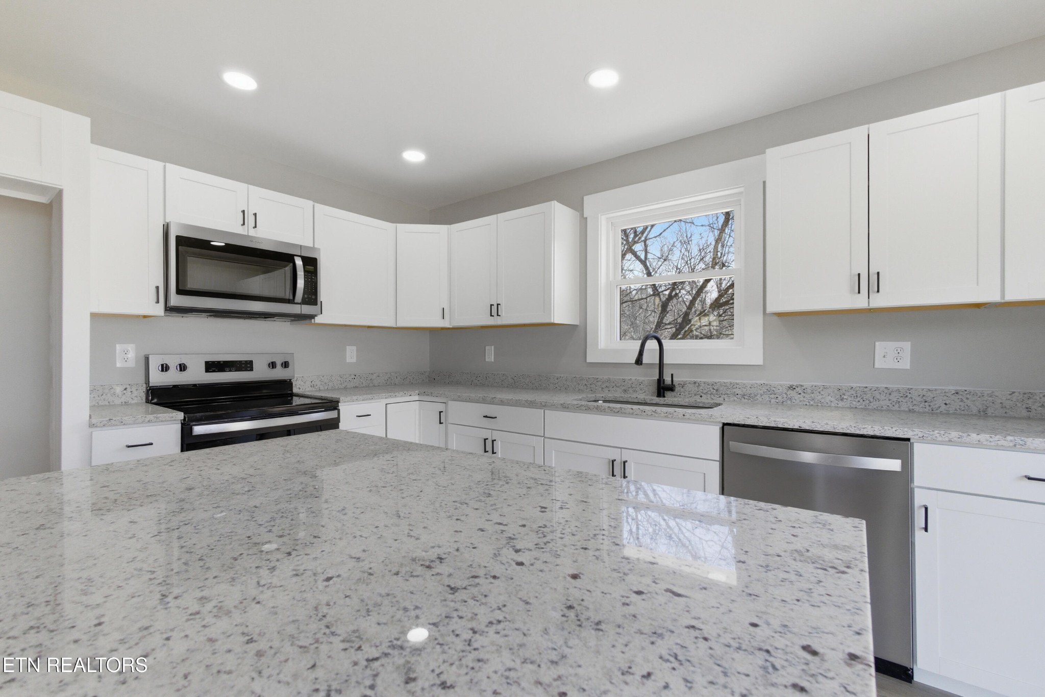 2241 Woods-Smith Road Knoxville, TN 37921 - Photo 12 of 37 a kitchen with stainless steel appliances granite countertop a stove top oven a sink a granite counter tops and a view of living room