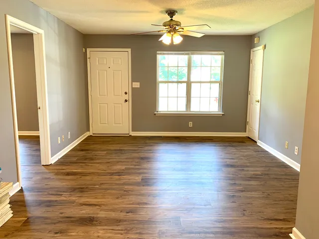 an empty room with wooden floor and windows