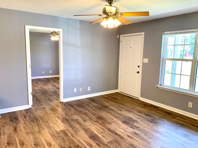 a view of an empty room with window and wooden floor