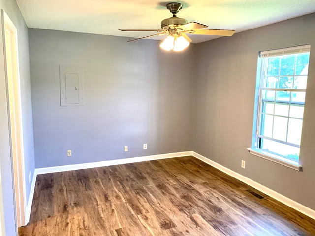 an empty room with windows and fan