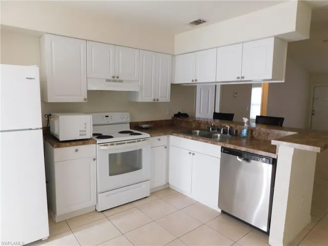 a kitchen with granite countertop white cabinets and white appliances