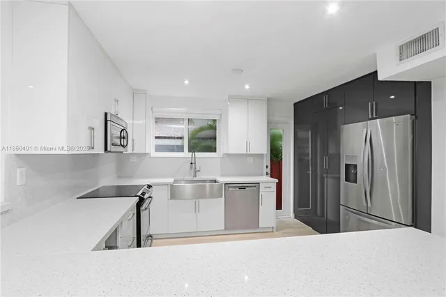a kitchen with stainless steel appliances kitchen island a refrigerator sink and cabinets