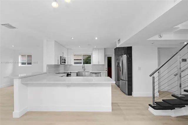 a large white kitchen with a sink and a refrigerator
