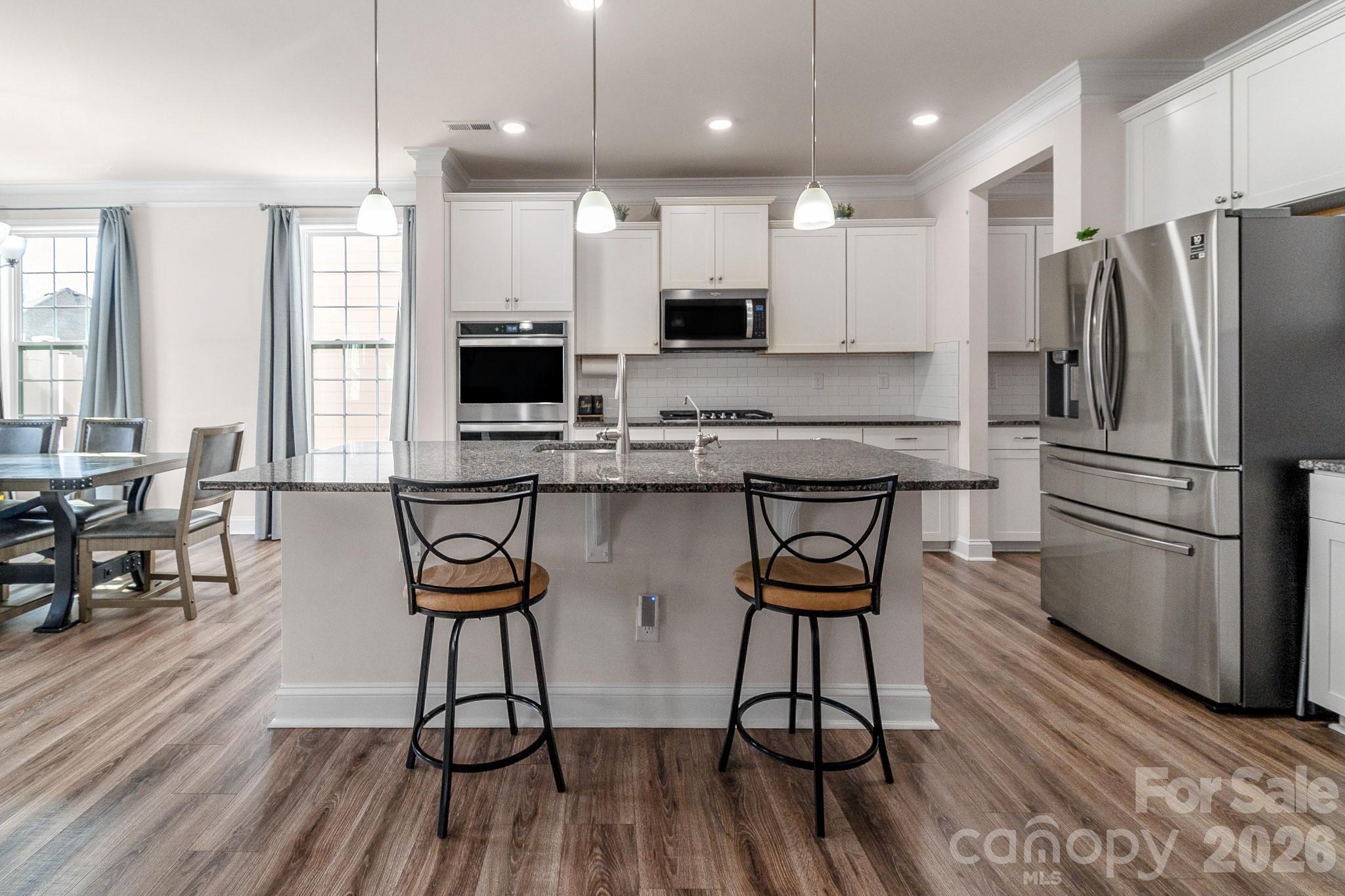 1630 Fitzgerald Street Northwest Concord, NC 28027 - Photo 10 of 38 a kitchen with stainless steel appliances a refrigerator a stove a sink dishwasher a dining table and chairs with wooden floor