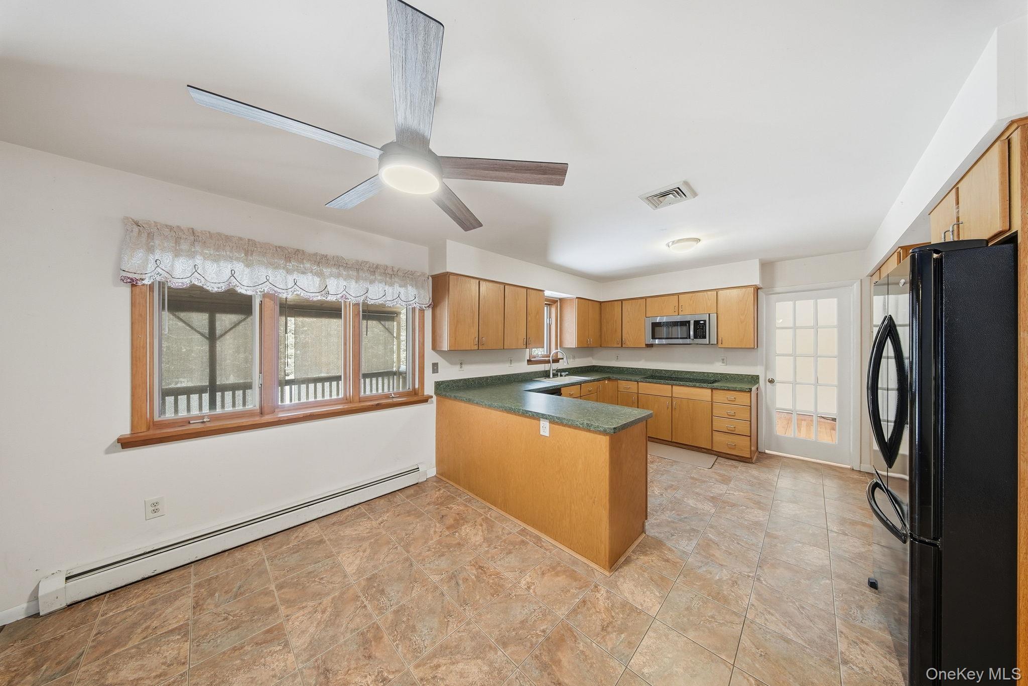 139 Renner Road Mountain Dale, NY 12763 - Photo 14 of 49 Kitchen featuring a peninsula, a baseboard heating unit, black appliances, a ceiling fan, and light brown cabinetry