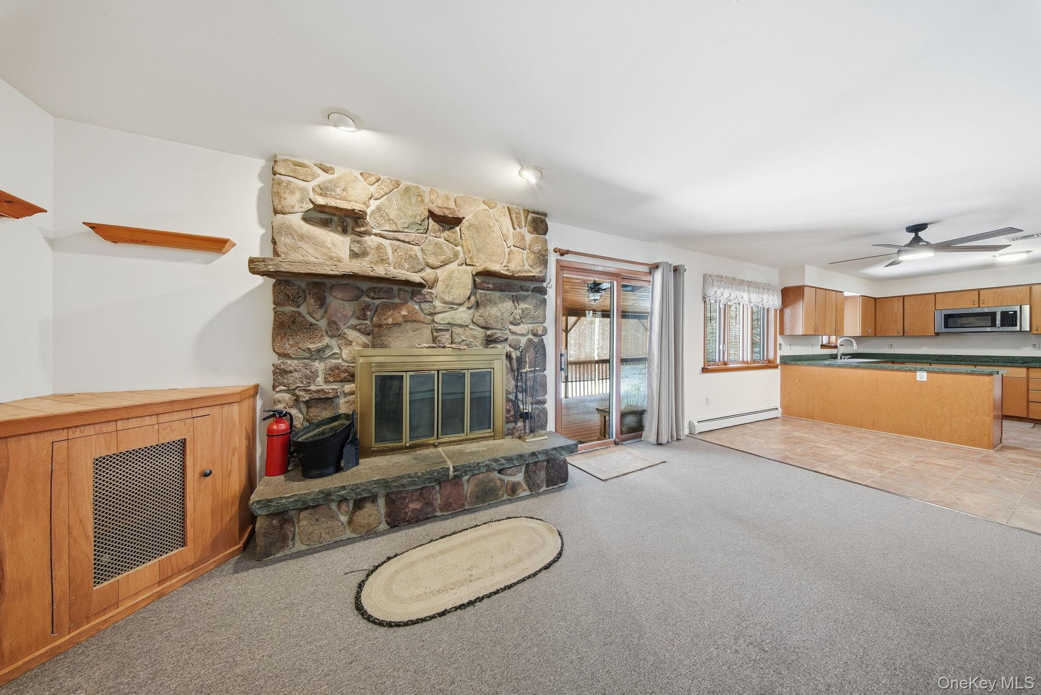 139 Renner Road Mountain Dale, NY 12763 - Photo 17 of 49 Featuring a hand picked fieldstone fireplace, light colored carpet, a baseboard heating