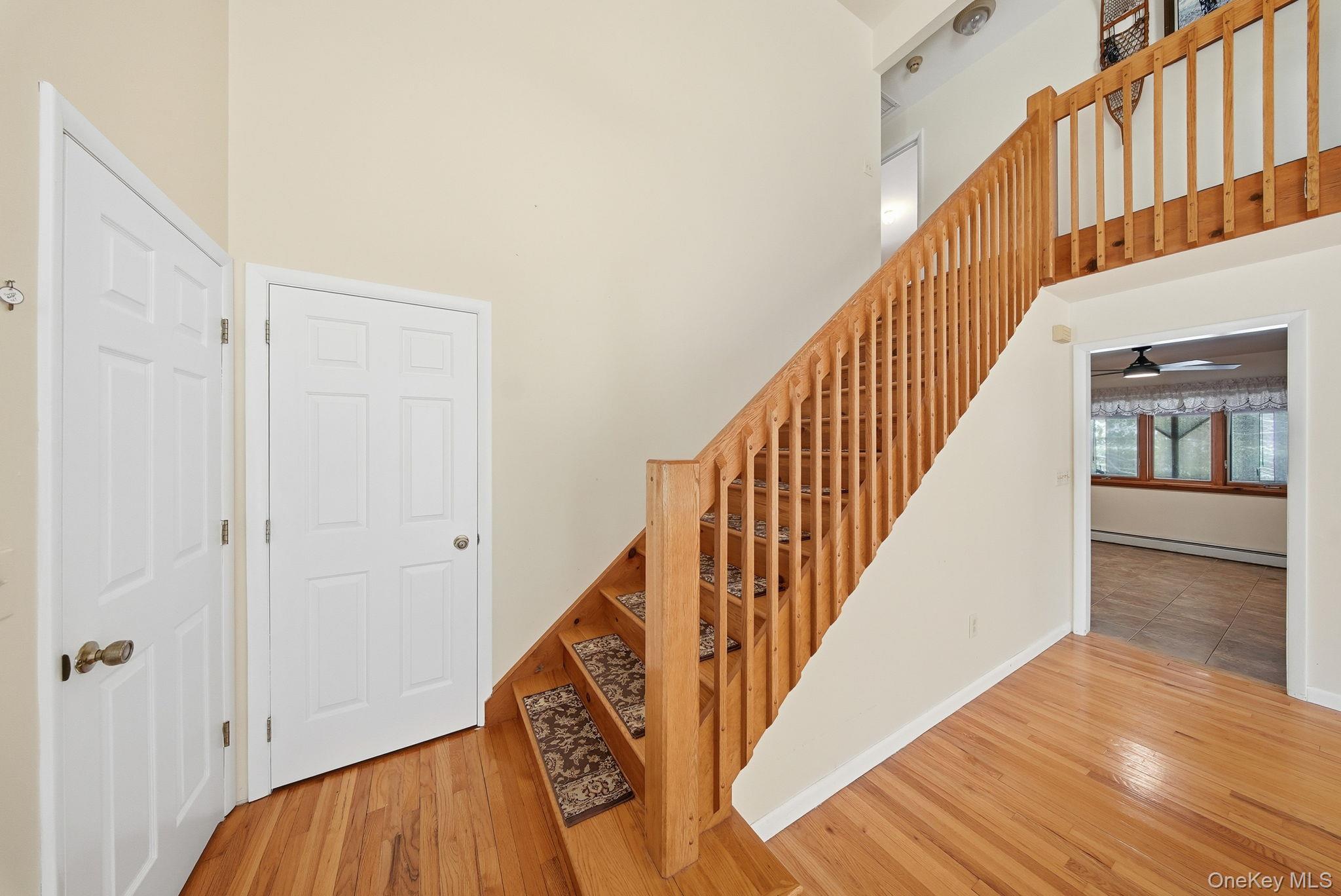 139 Renner Road Mountain Dale, NY 12763 - Photo 5 of 49 Stairway featuring a towering ceiling, wood-type flooring, a baseboard radiator, and a ceiling fan