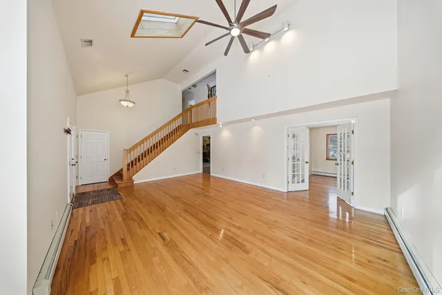 a view of empty room with wooden floor and fan
