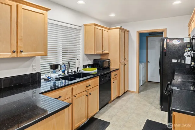 a kitchen with stainless steel appliances granite countertop a refrigerator a sink dishwasher and white cabinets with wooden floor