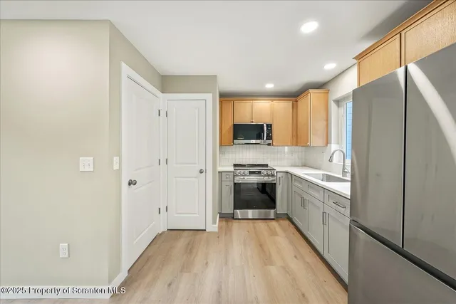 a view of a kitchen with a refrigerator a ceiling fan and wooden floor