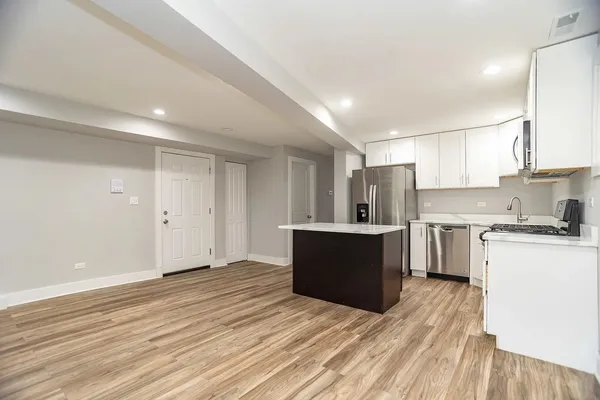 a view of kitchen with stainless steel appliances granite countertop a stove top oven a sink dishwasher and a refrigerator with wooden floor