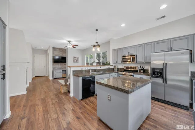 a kitchen with stainless steel appliances kitchen island granite countertop wooden floors and white cabinets