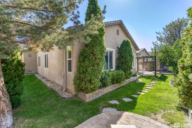 a backyard of a house with table and chairs plants and large trees