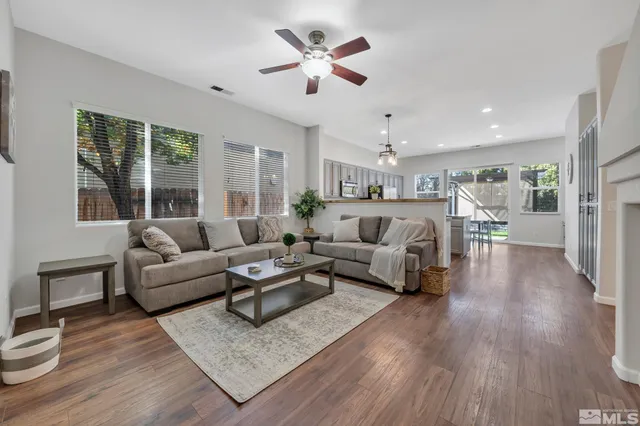 a living room with furniture a fireplace and a ceiling fan
