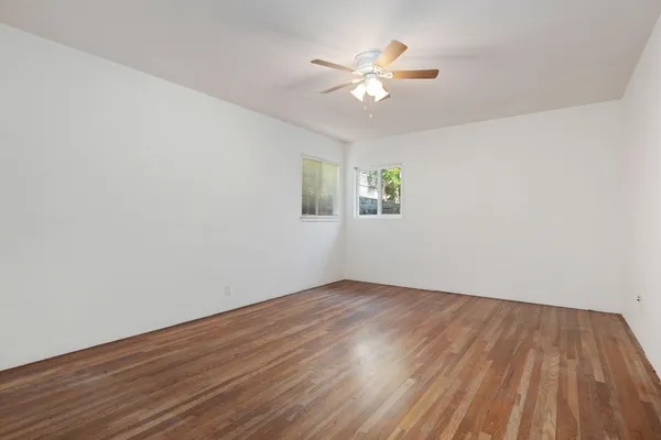 a view of an empty room with wooden floor and a window