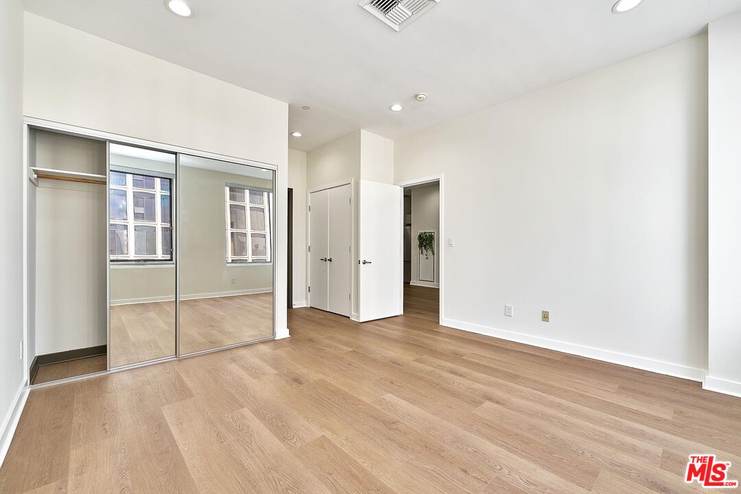 3810 Wilshire Boulevard, Unit 404 Los Angeles, CA 90010 - Photo 13 of 43 an empty room with wooden floor and mirror
